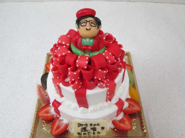 還暦祝いのパーティーケーキに 赤いリボンデコの2段ケーキにちゃんちゃんこ姿の女性を立体で 大阪市東住吉区 パティスリーデコ